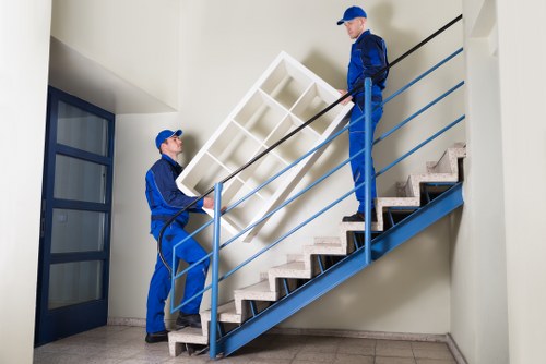 Professional movers carrying furniture through a Stockwell property staircase